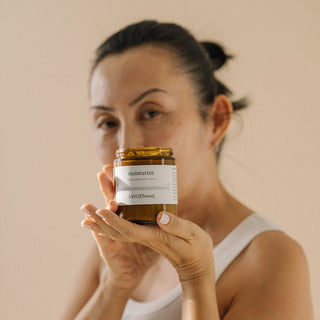 A woman holding a jar of Chardonnay body cream, with the product label visible.