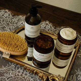 korean body care ritual products including bottles, jar, and brush on a decorative tray with lace background.