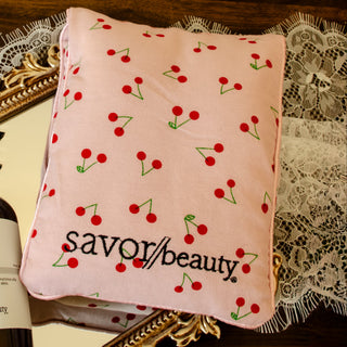 Skincare bottle and cherry-patterned pillow on a decorative tray with lace