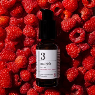 Centered flatlay of Raspberry Seed Serum surrounded in an abundance of fresh bright raspberries