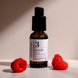 Bottle of Raspberry Seed Serum with 3 raspberries on a neutral background