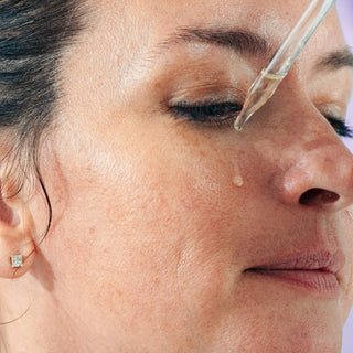 Woman applying face oil to cheek