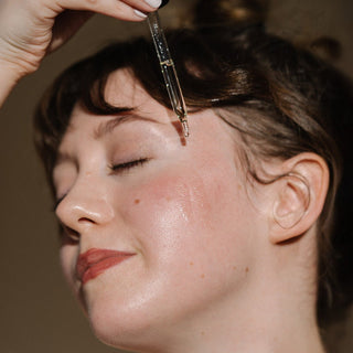Young woman applying cleansing oil to face