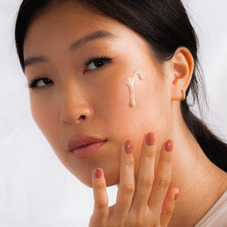 Woman with swatch of pearl cleansing cream dripping down face.