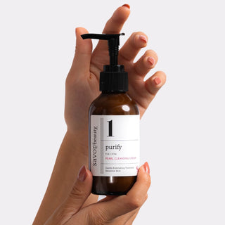 Hands holding bottle of Pearl Cleansing Cream.