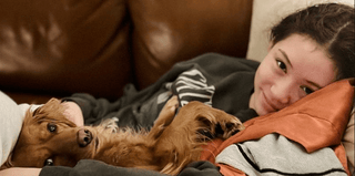 Teen snuggling dog