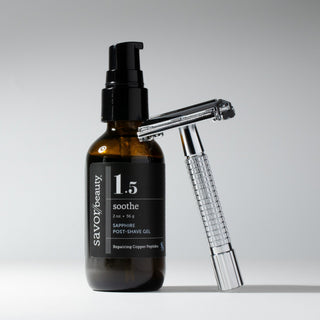 Bottle of 'savor beauty' post-shave gel with a silver razor on a gray background