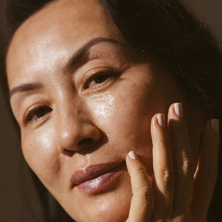 Woman with hand on face against a brown background