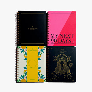 Four spiral-bound planners arranged in a 2x2 grid on a light gray background. The top-left planner is black with gold lettering reading 'MY NEXT 90 DAYS'.