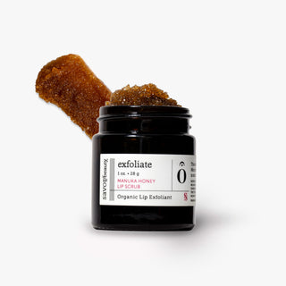A jar of Savor Beauty organic exfoliate lip scrub with a thick brown scrub texture visible above the open jar, set against a clean white background.