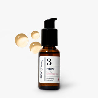 Savor Beauty Renew Pumpkin Seed Serum in a 1 oz amber glass bottle with a black pump dispenser, shown on a light gray background with three floating golden droplets.
