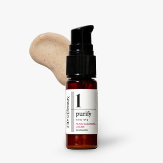A small amber glass pump bottle labeled 'savor beauty 1 purify Pearl Cleansing Cream' stands on a light gray background with a beige cream smear behind it.
