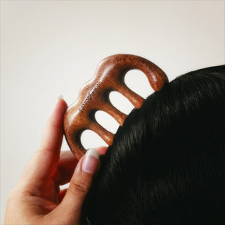 Person using savor beauty scalp gua sha on their hair against a neutral background