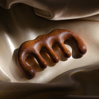 Brown wooden scalp gua sha on a beige fabric background