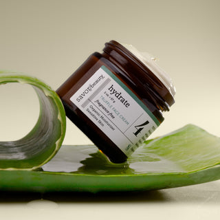 Fragrance-free Truffle Face Cream jar on a green peeled aloe leaf with a beige background