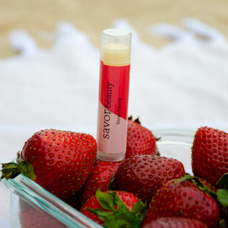 Organic strawberry lip balm sitting atop fresh strawberries