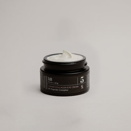 Black, open jar of eye cream labeled 