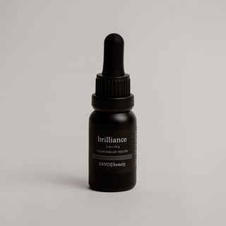 Black dropper bottle labeled 'brilliance' on a gray background
