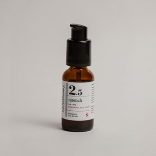 Skincare serum bottle labeled '2.5 quench' on a gray background