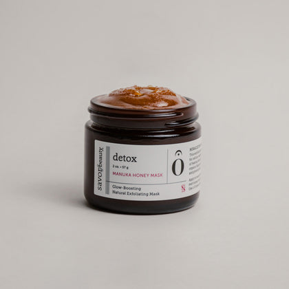 Open jar of manuka honey face mask on gray background