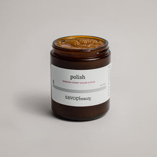 Skincare jar labeled 'Polish manuka honey sugar scrub' on a light gray background