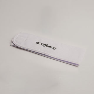 White terry cloth headband with "savor beauty" logo embroidered