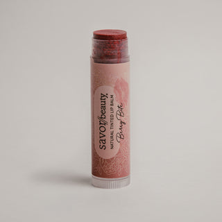Lip balm stick with savor beauty brand name on a light gray background