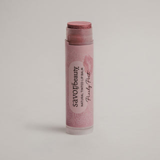 Pink lip balm with 'savor beauty' branding on a light gray background