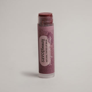 Lip balm stick with a purple label on a light gray background