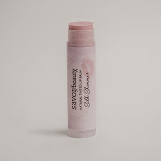 Lip balm stick with savor beauty brand name on a light gray background