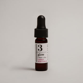 Bottle of '3 glow' skincare serum on a light gray background