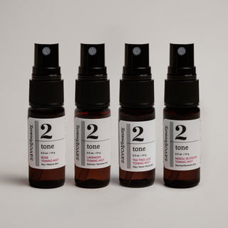 Four bottles of '2 tone' skincare product on a light gray background