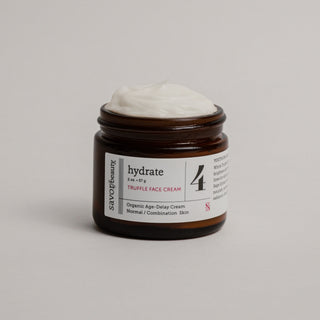 Open jar of truffle face cream against a grey background