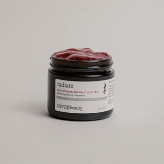 Open jar of skincare product labeled "radiate" on a neutral background