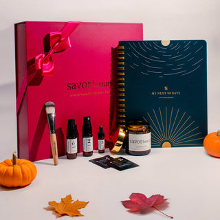Savor Beauty products with pink box, notebook, and decorative leaves on a white background.