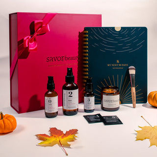 Savor Beauty product set with full bottles, a notebook, and decorative leaves on a white background.