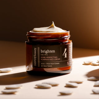 Jar of pumpkin face cream with a swatch on top, surrounded by pumpkin seeds on a warm-toned background.