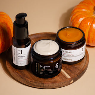 Three skincare products on a wooden tray with pumpkins in the background