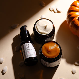 Three skincare products on a textured surface with a warm light