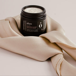 Black jar of neck cream wrapped in a champagne colored silk scarf