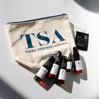 Cosmetic bag with 'TSA' branding and savor beauty travel skincare products on a light background