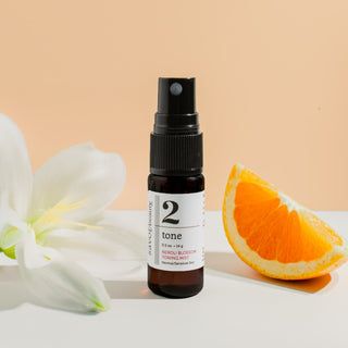Skincare bottle labeled '2 tone' with an orange slice and white flowers on a beige background