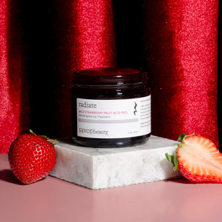 Open jar of strawberry peel with strawberries on a red curtain background