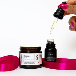 Hand pouring dropper into bottle with skincare products and ribbons on a white background