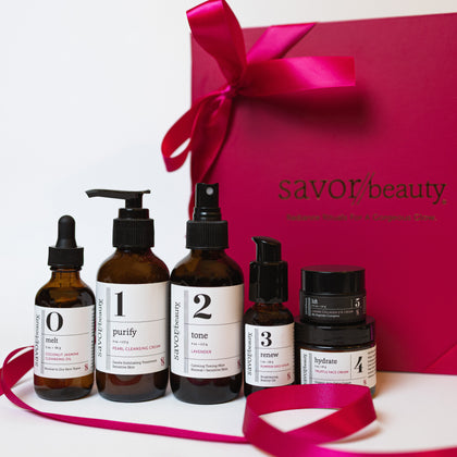 Set of skincare products with labeled bottles in front of a Savor Beauty box.