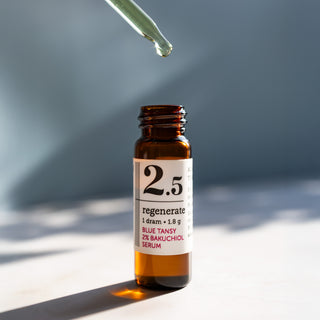 close up shot of 1 dram glass bottle of savor beauty regenerate blue tansy 2% bakuchiol serum on a sunny, light blue backround