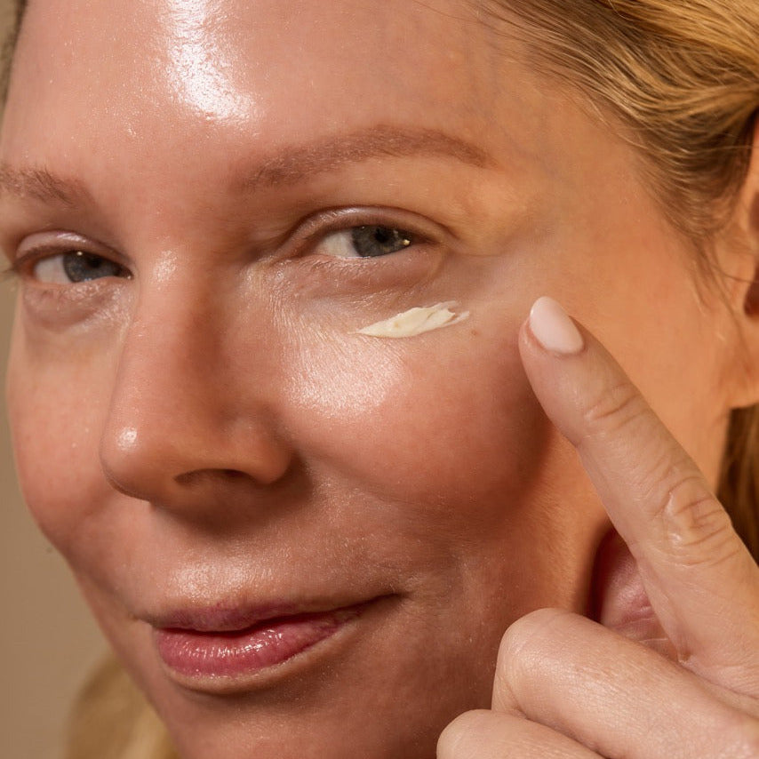 Woman applying cream to her face with a finger