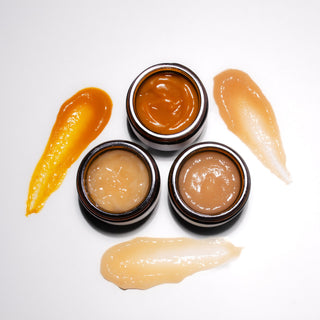 three small jars with face masks on a white background
