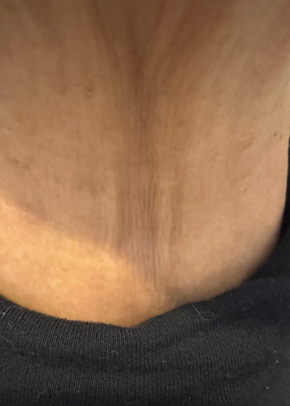 Close-up of a person's neck and upper chest wearing a black crew-neck t-shirt.
