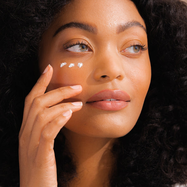 Woman applying eye cream to her face with a blurred background